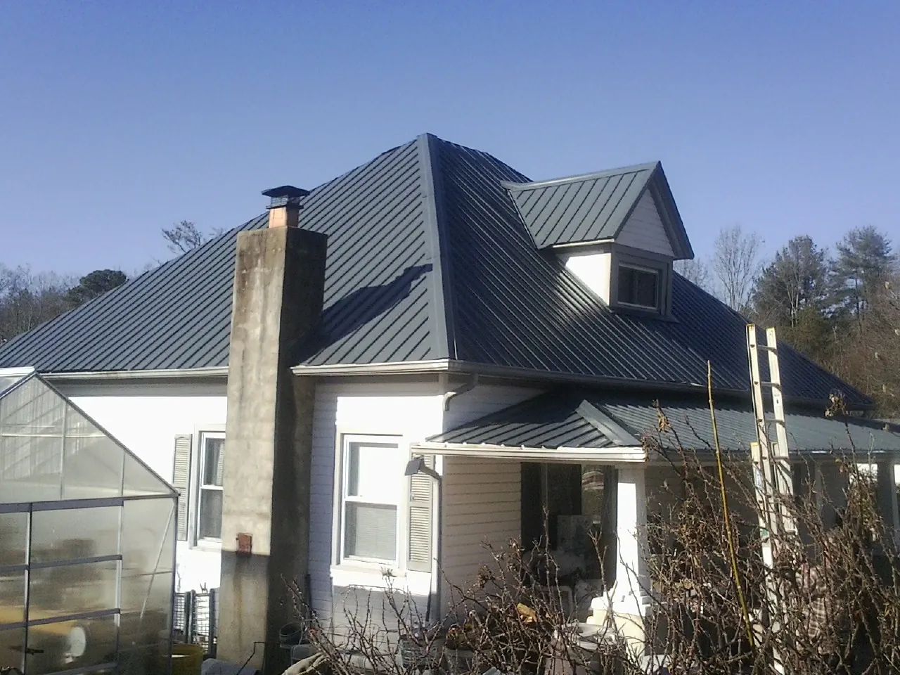 Dark blue standing seam metal roof on a white farmhouse with dormer — Slate & Tile Roof Repair by Roofing Brothers in North Granby