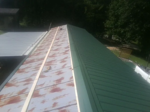 Old rusted panels beside newly installed green metal roofing — Wind Damage Roof Repair by Roofing Brothers in North Granby