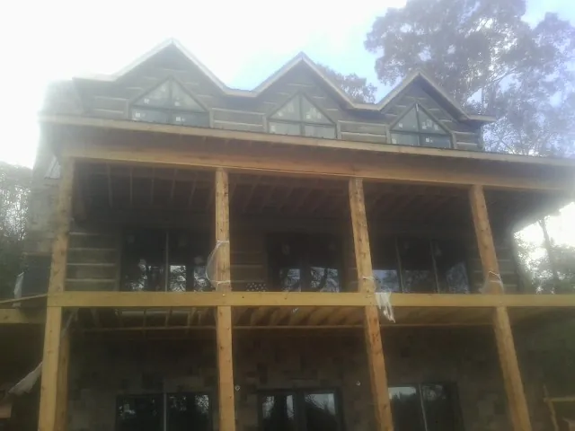 Dormers and porch framing on a large log home under construction — Roof Coating work by our crew in North Granby
