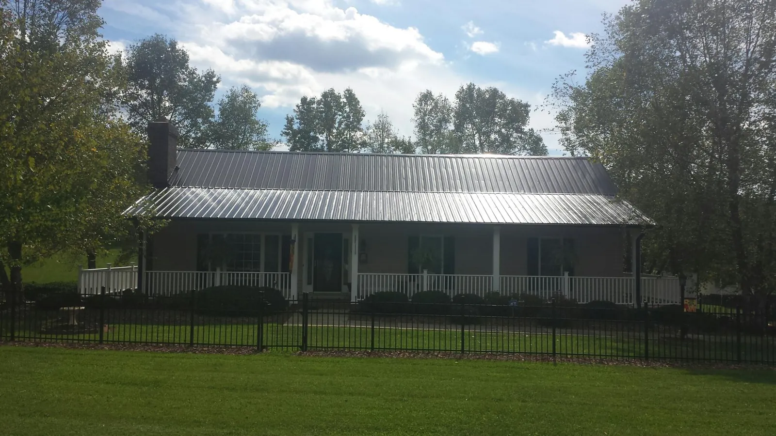 Gray metal roof on a brick ranch with a full width front porch — Gutter Guard Installation work by our crew in North Granby