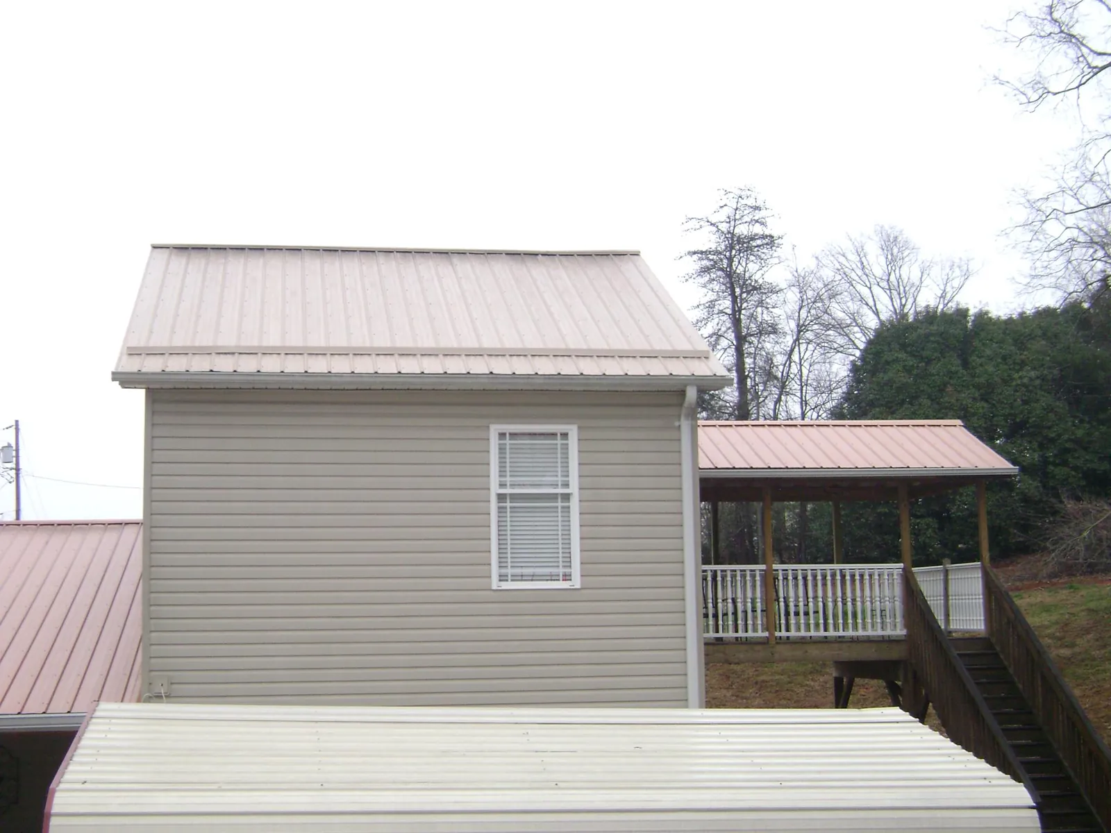 Tan metal roofs on a two story addition and attached porch, from a Roof Replacement job in North Granby