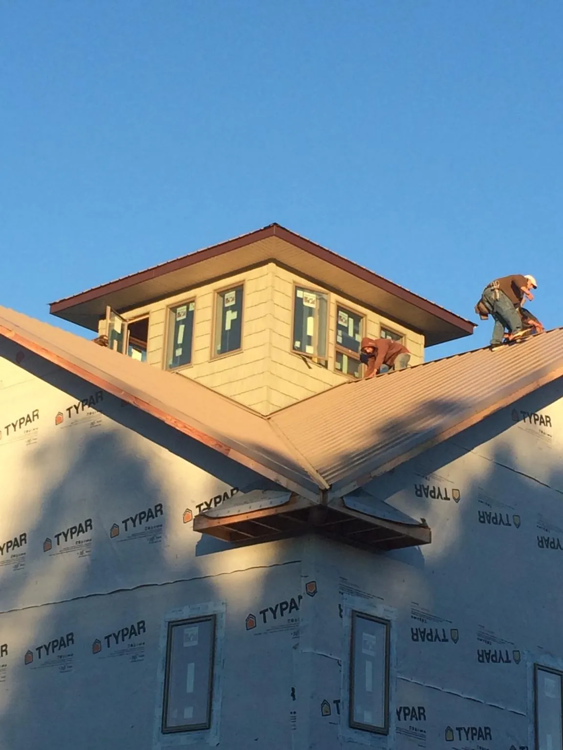 Roofers working around a rooftop cupola on a new metal roof at sunset — Roof Waterproofing in North Granby by Roofing Brothers